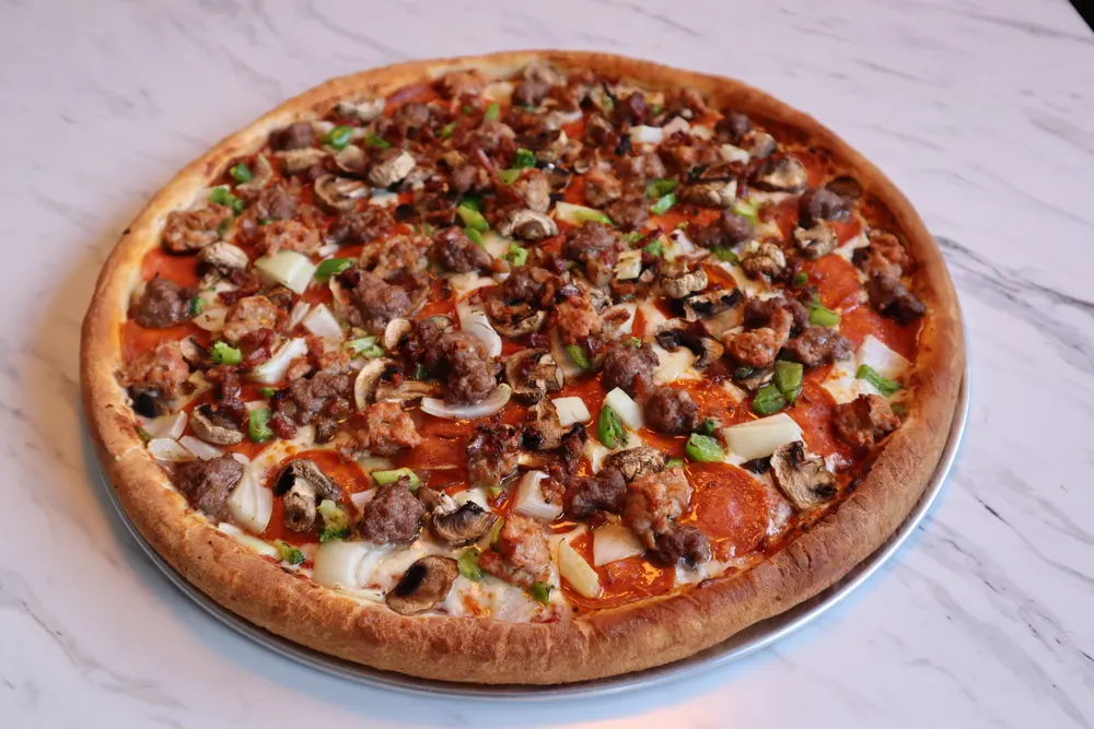 A whole cheese pizza on a marble counter